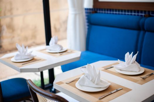 Cozy restaurant table setting with blue seating and artistic folded napkins, creating a stylish dining ambiance.