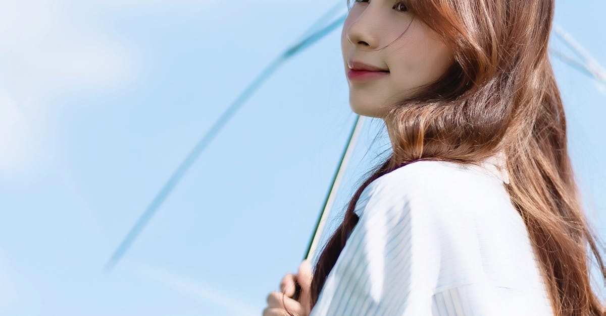 Photo by lii Chun Young woman with long hair holding a clear umbrella on a sunny day.