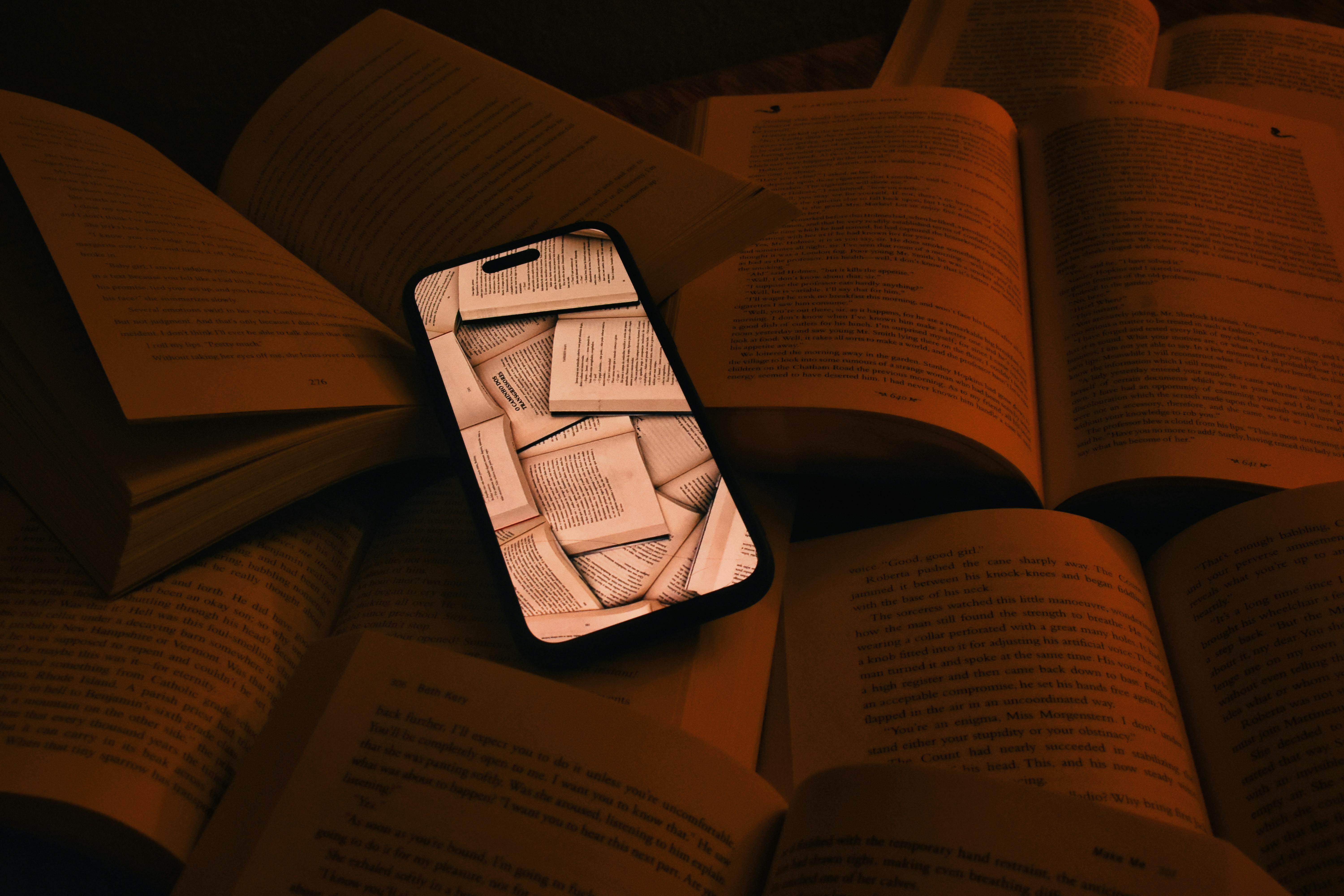 A smartphone displaying pages lies among open books, symbolizing digital integration.