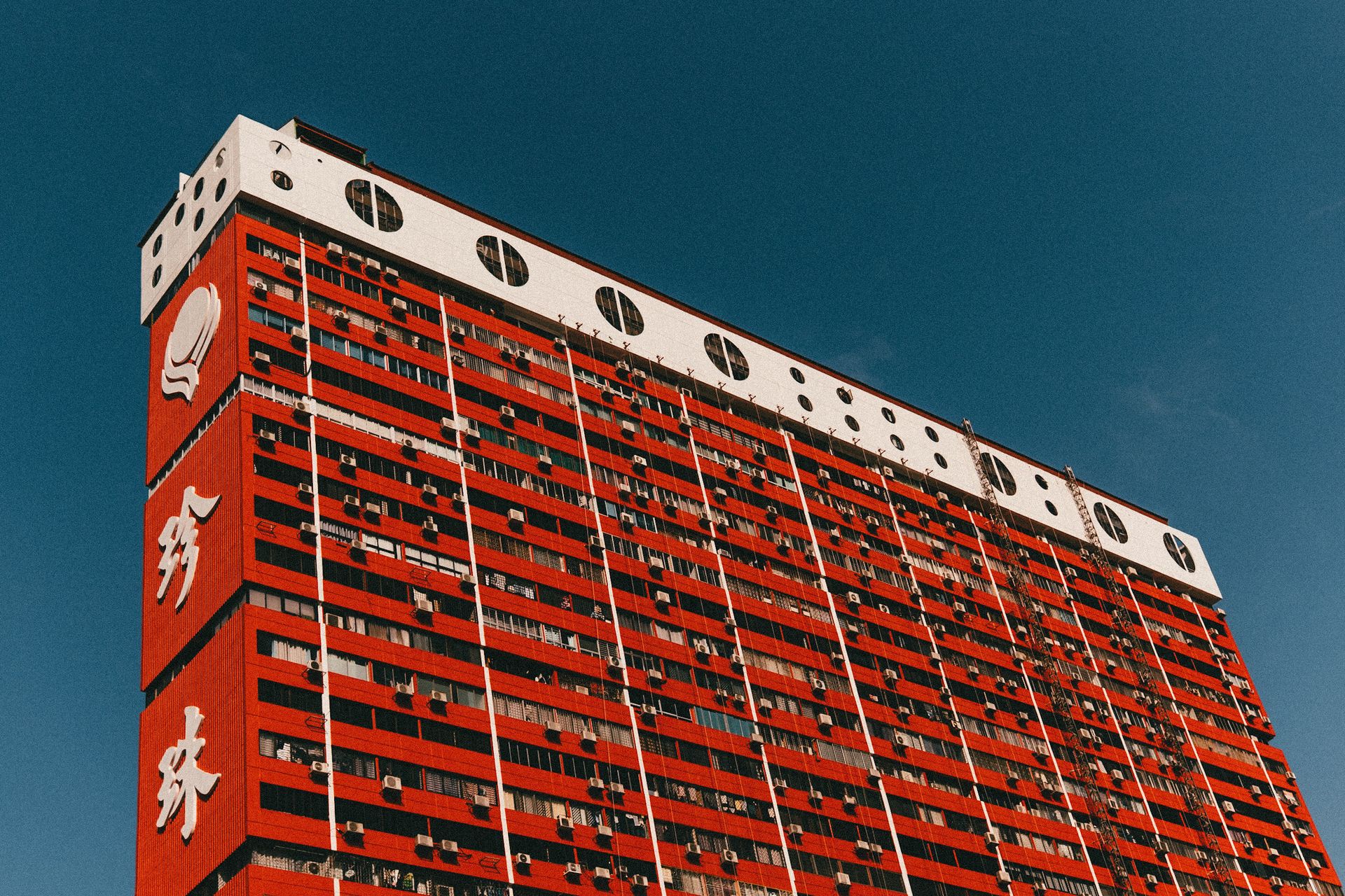 A striking red residential building with architectural details against a clear blue sky.