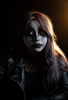 Dramatic portrait featuring intricate Halloween makeup under moody lighting.