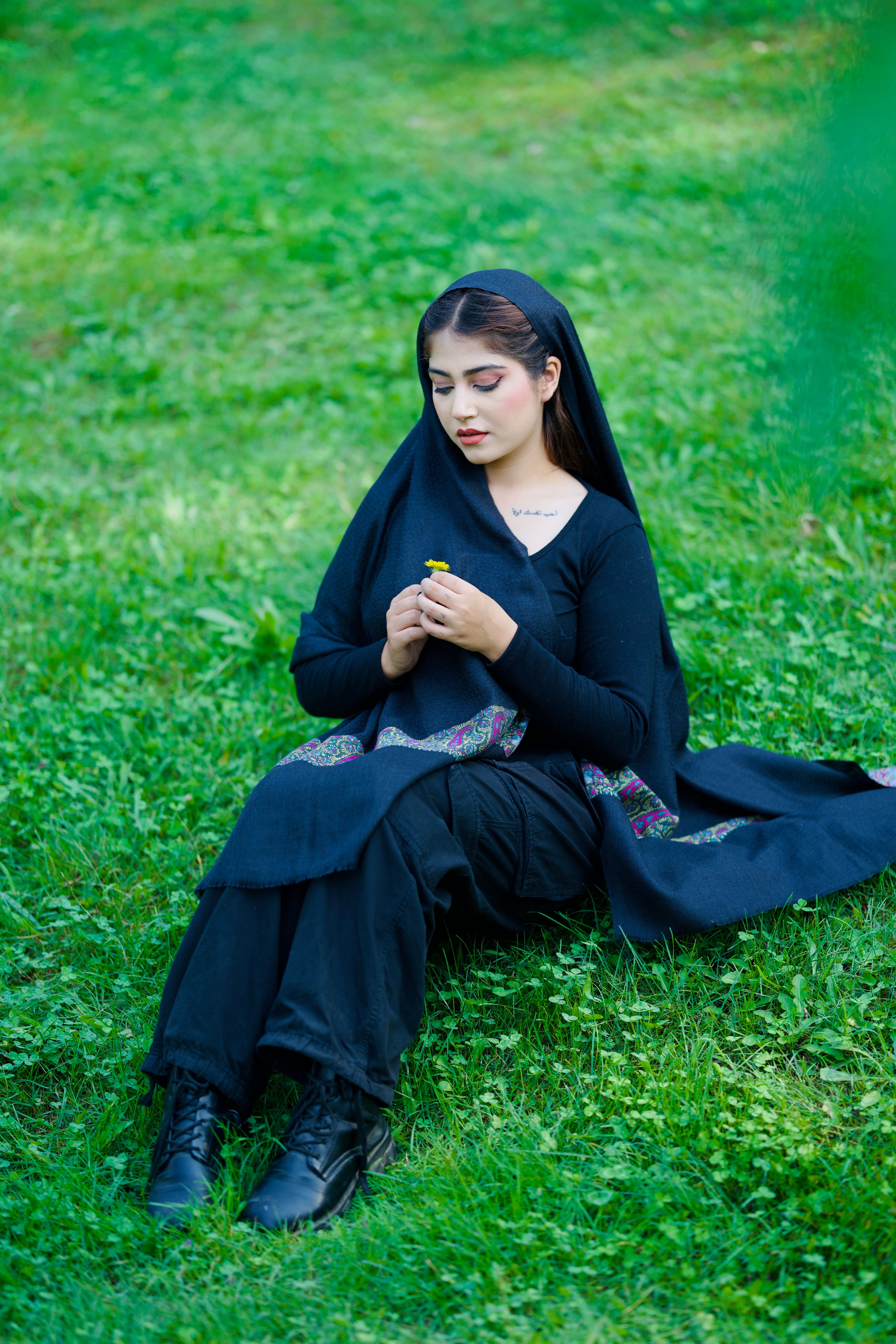A serene portrait of a woman seated on grassy field in Kashmir, India.