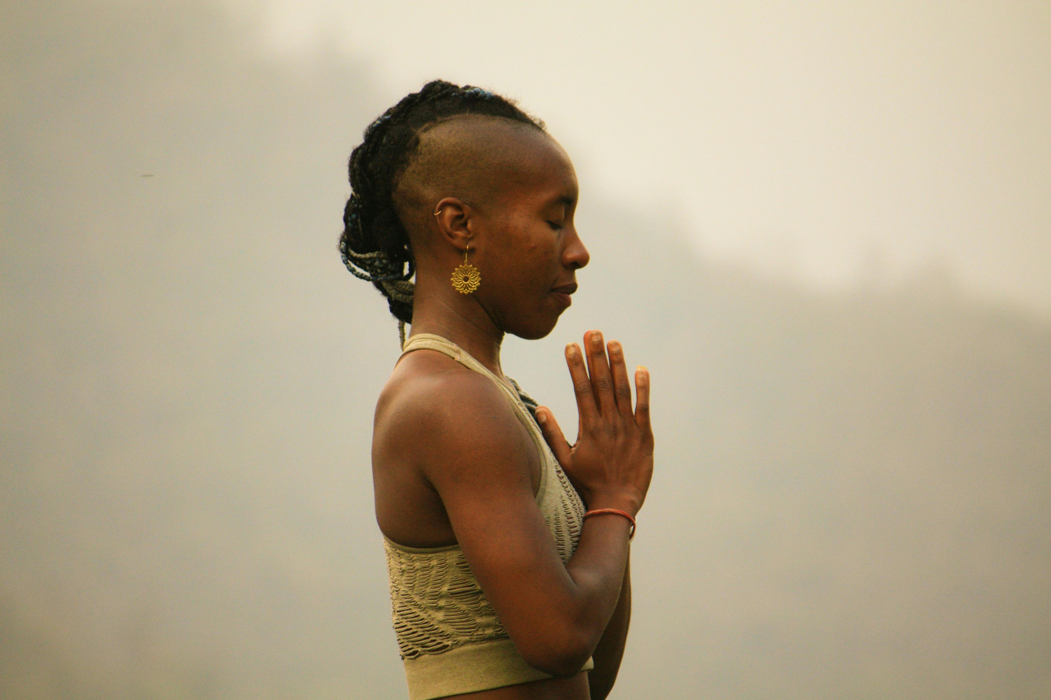 Woman practicing yoga outdoors with hands in prayer position in Rishikesh, India.
