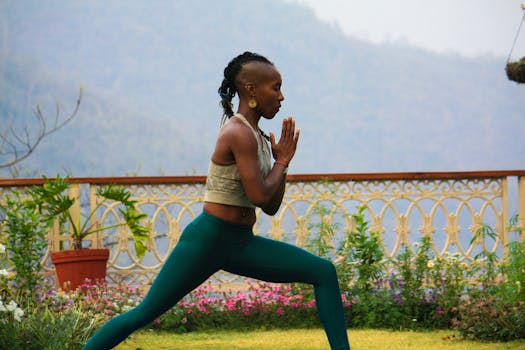 A woman practices yoga outdoors in Rishikesh, India, surrounded by vibrant flora, embodying tranquility and focus.