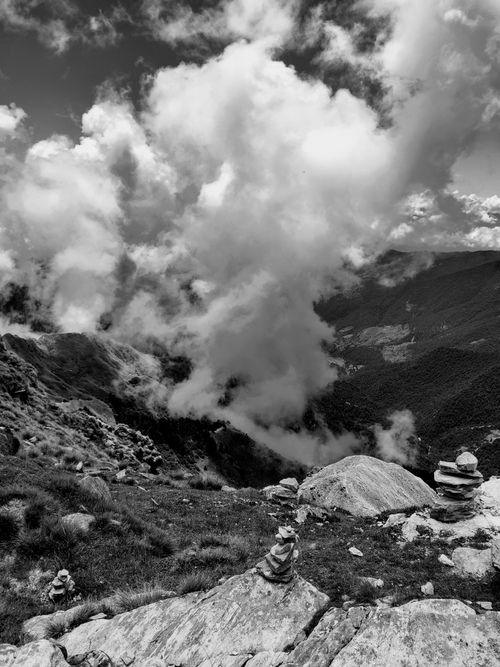 Free Black and white mountain scene with dramatic clouds and stone cairns. Rugged and serene. Stock Photo