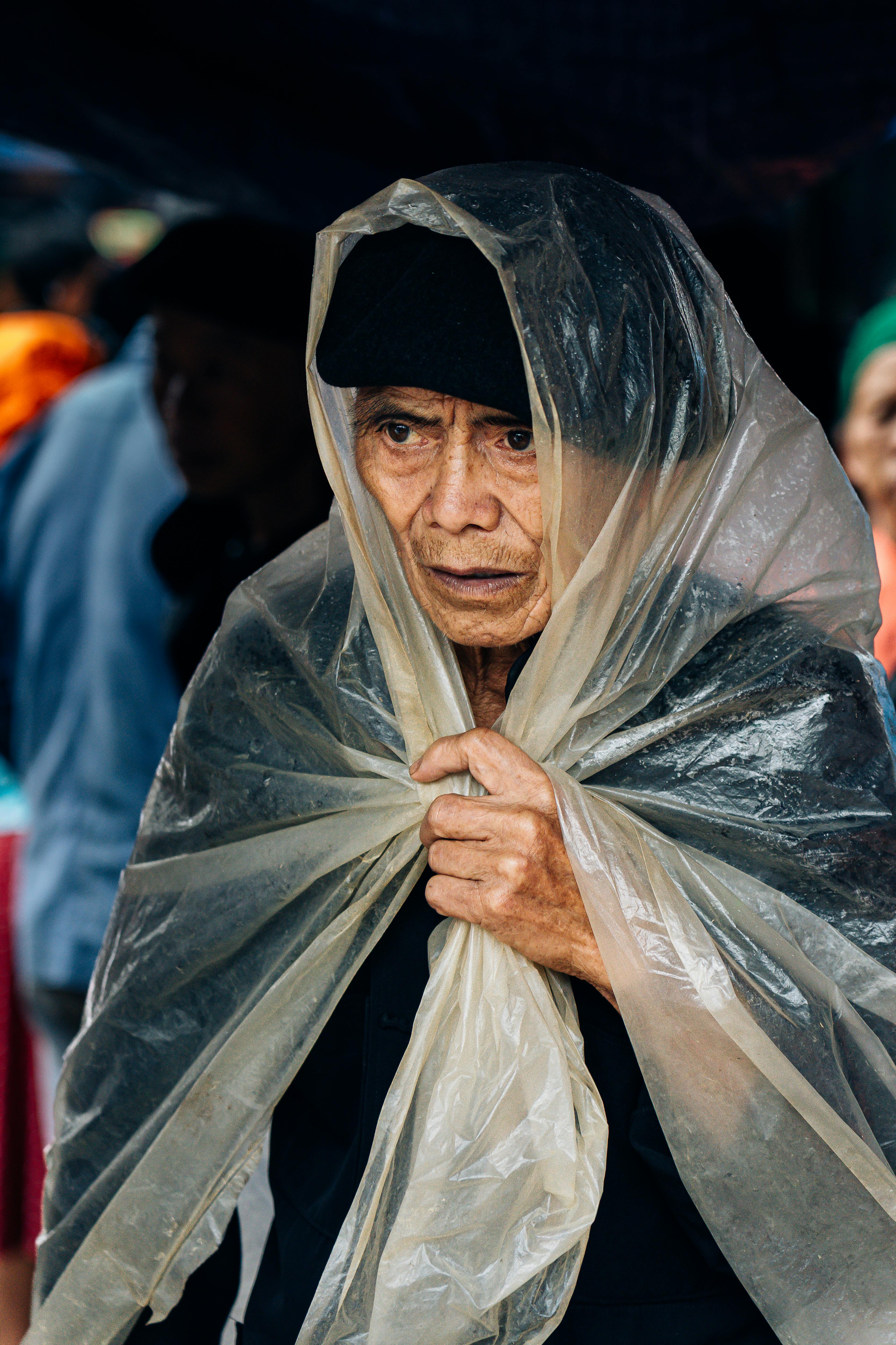 Elderly man wearing a rain poncho at a market in Ha Giang, Vietnam.