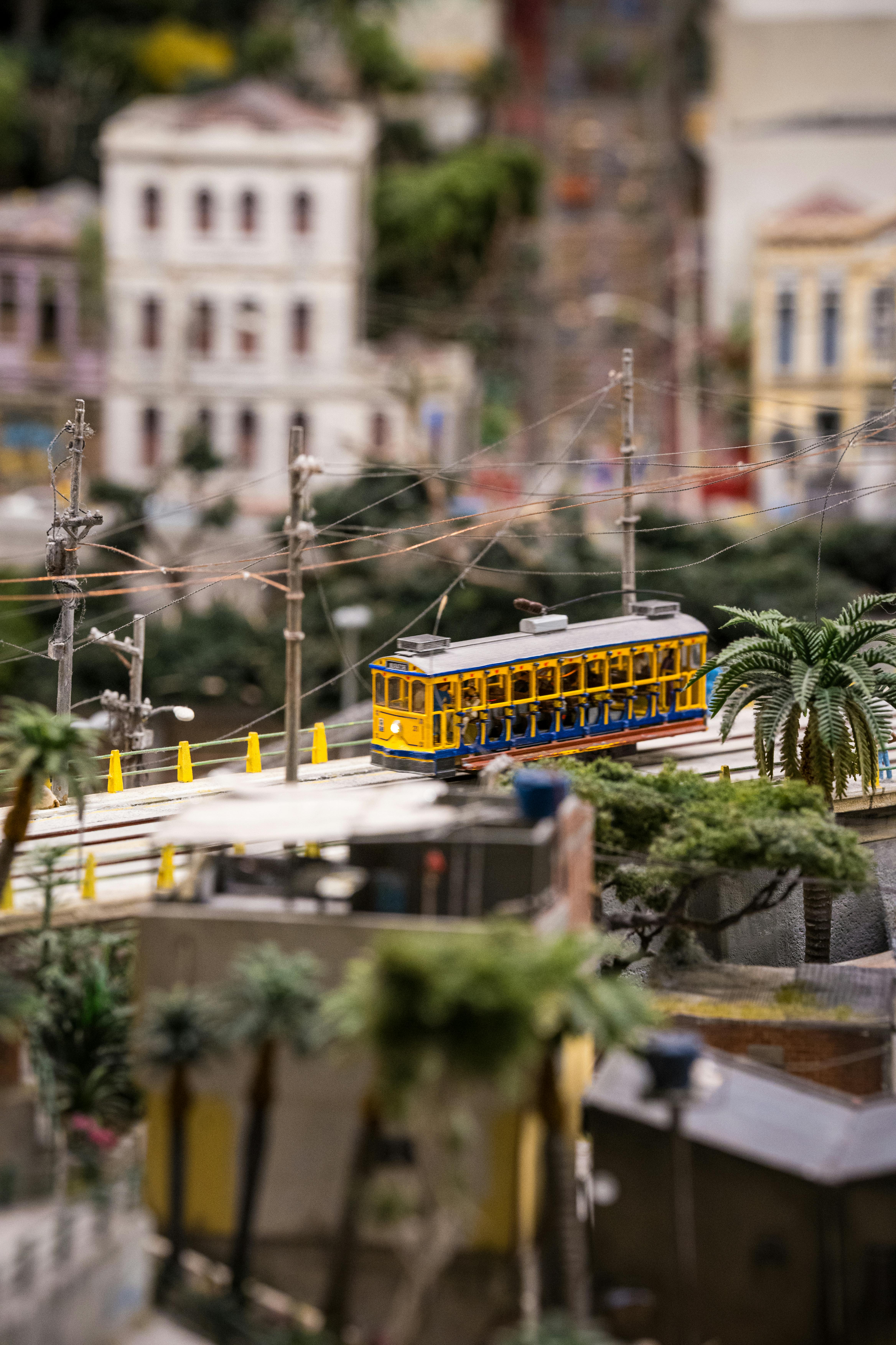 bezplatná Detailní pohled na miniaturní žlutou tramvaj projíždějící modelovým městským uličním prostředím. Základová fotografie