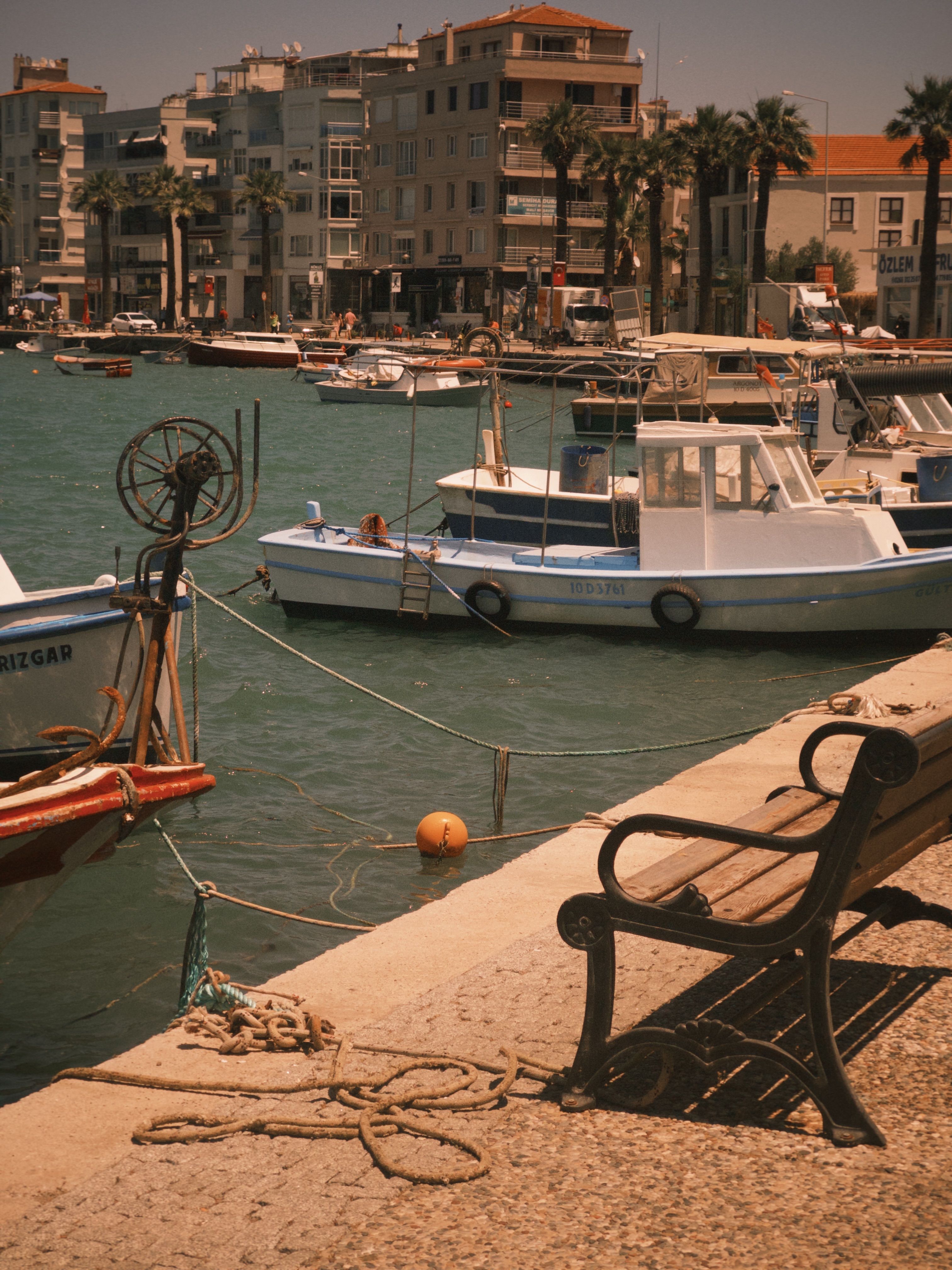 Serene Coastal Harbor View with Boats and Bench · Free Stock Photo