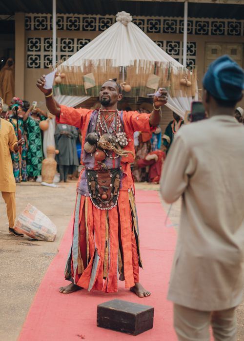 Free Man in traditional African attire performing a ceremony outdoors with audience. Stock Photo