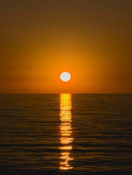A tranquil sunset over the ocean with a vibrant reflection on the water.