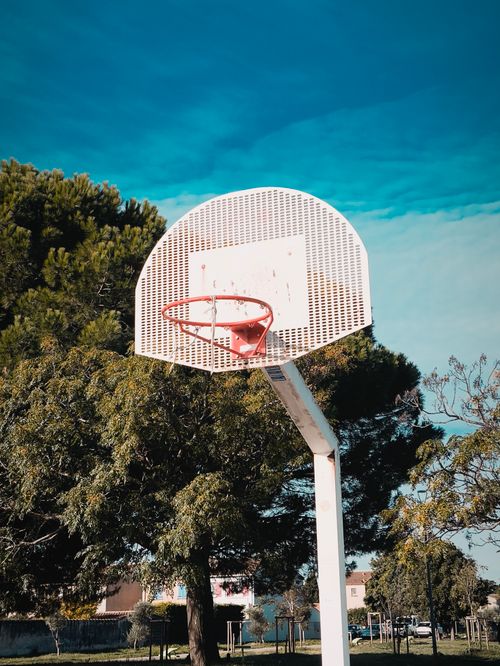Free A classic outdoor basketball hoop set against a vibrant blue sky, perfect for sports settings. Stock Photo