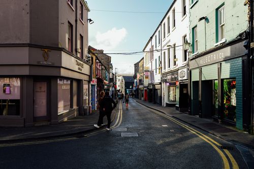Free A bustling urban street with shops and people, captured during the day with vibrant lighting. Stock Photo