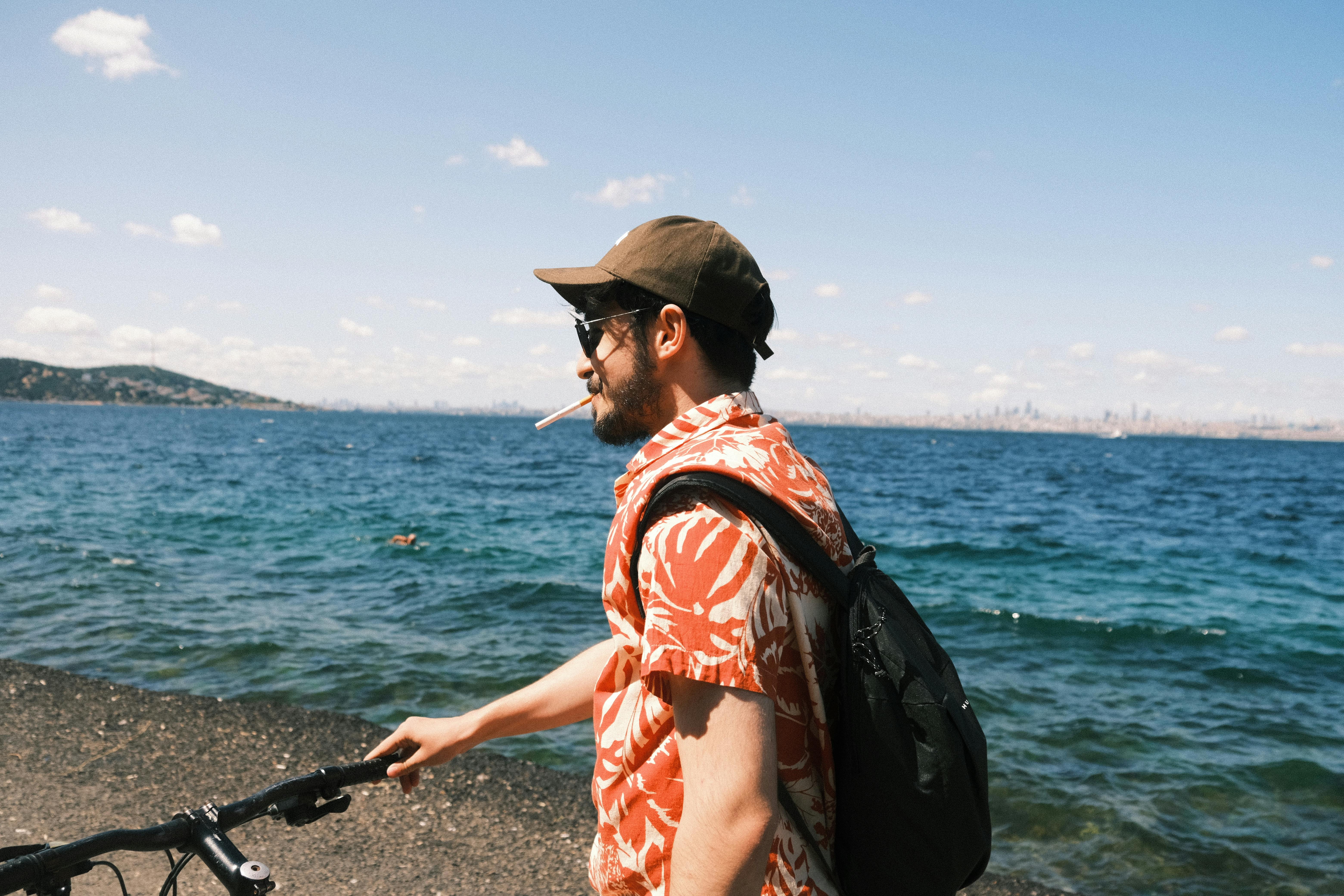 Young man with a bicycle and backpack relaxing by the sea in Burgazada, İstanbul on a sunny summer day.