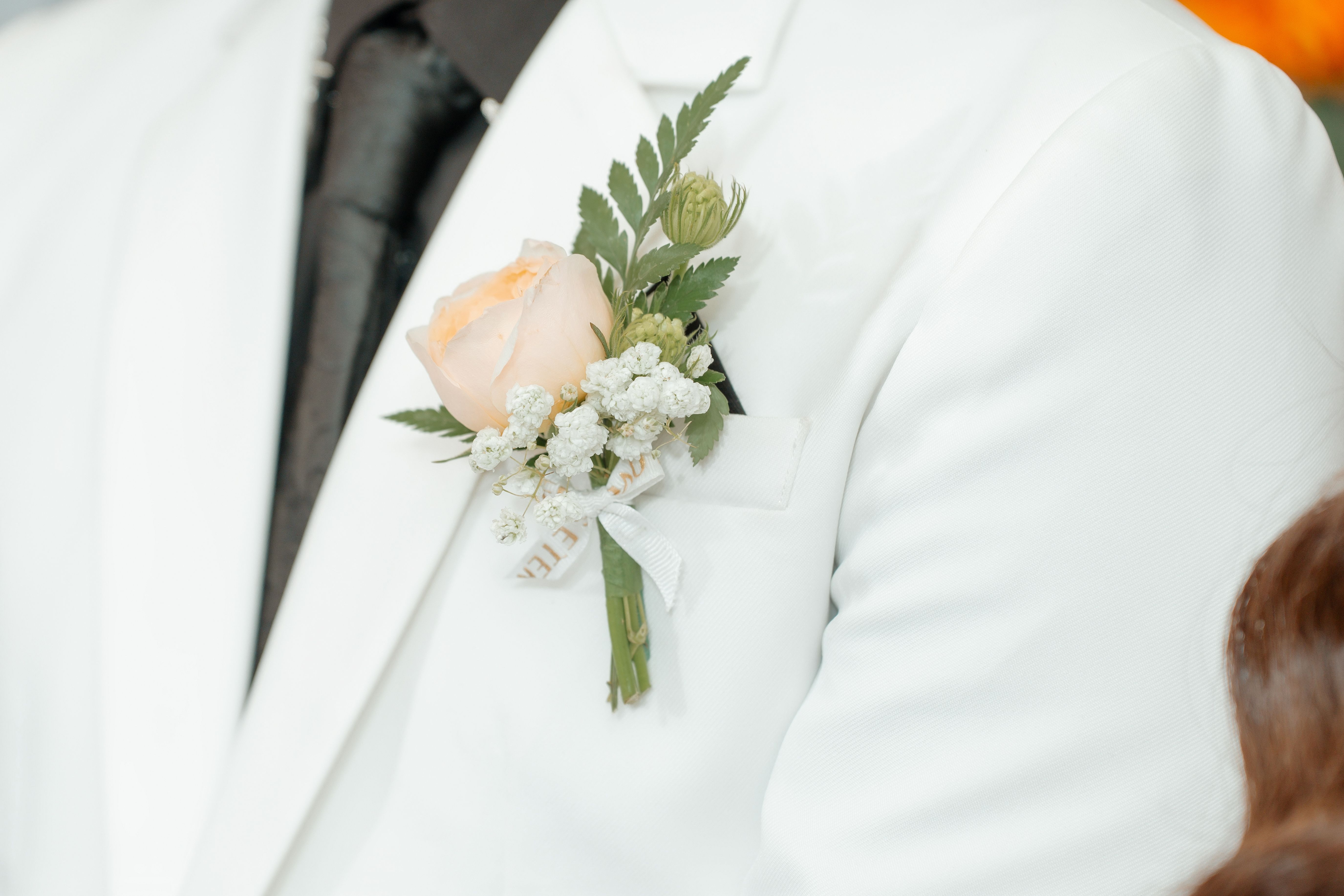 A handcrafted boutonniere with foliage and a single bloom