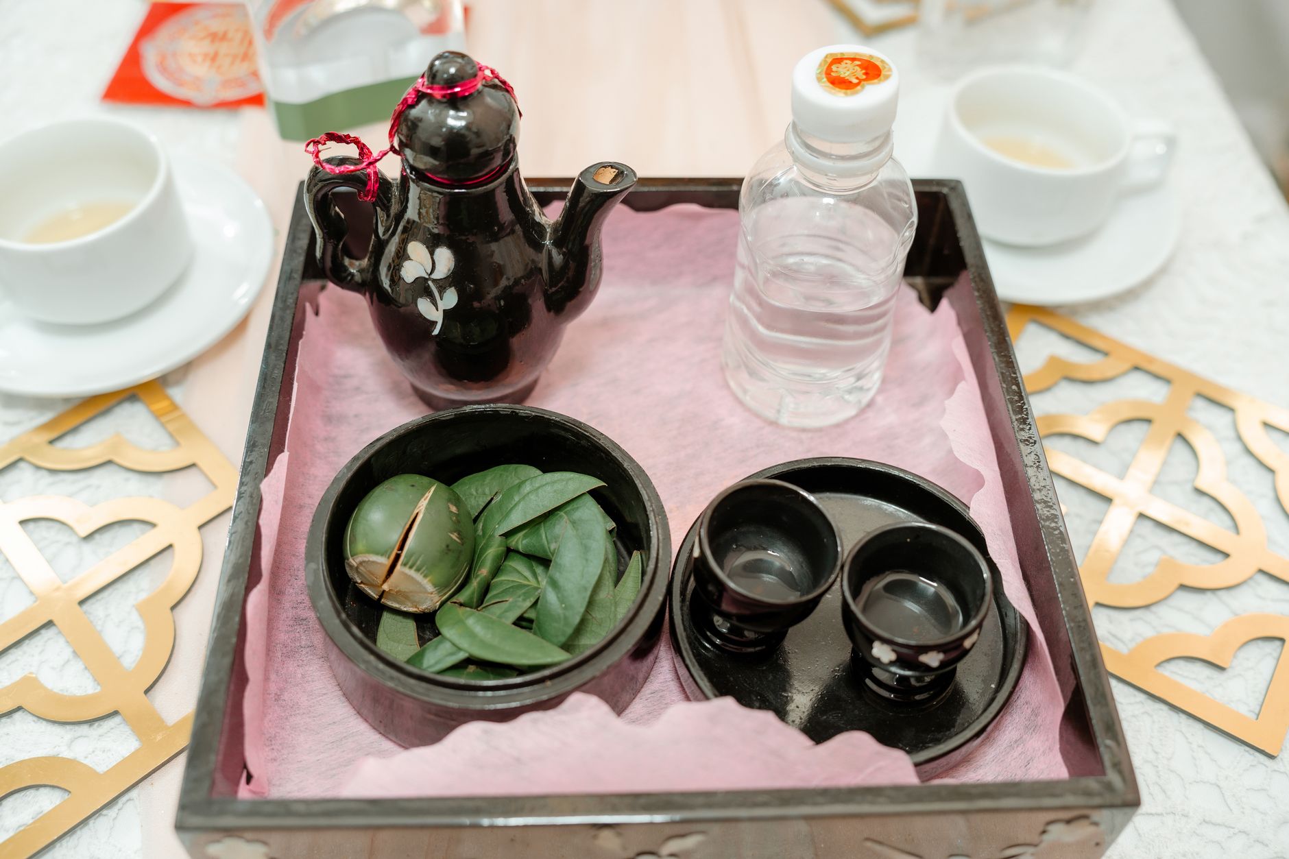 Elegant tea tray featuring a teapot, cups, and green leaves, perfect for cultural ceremonies.
