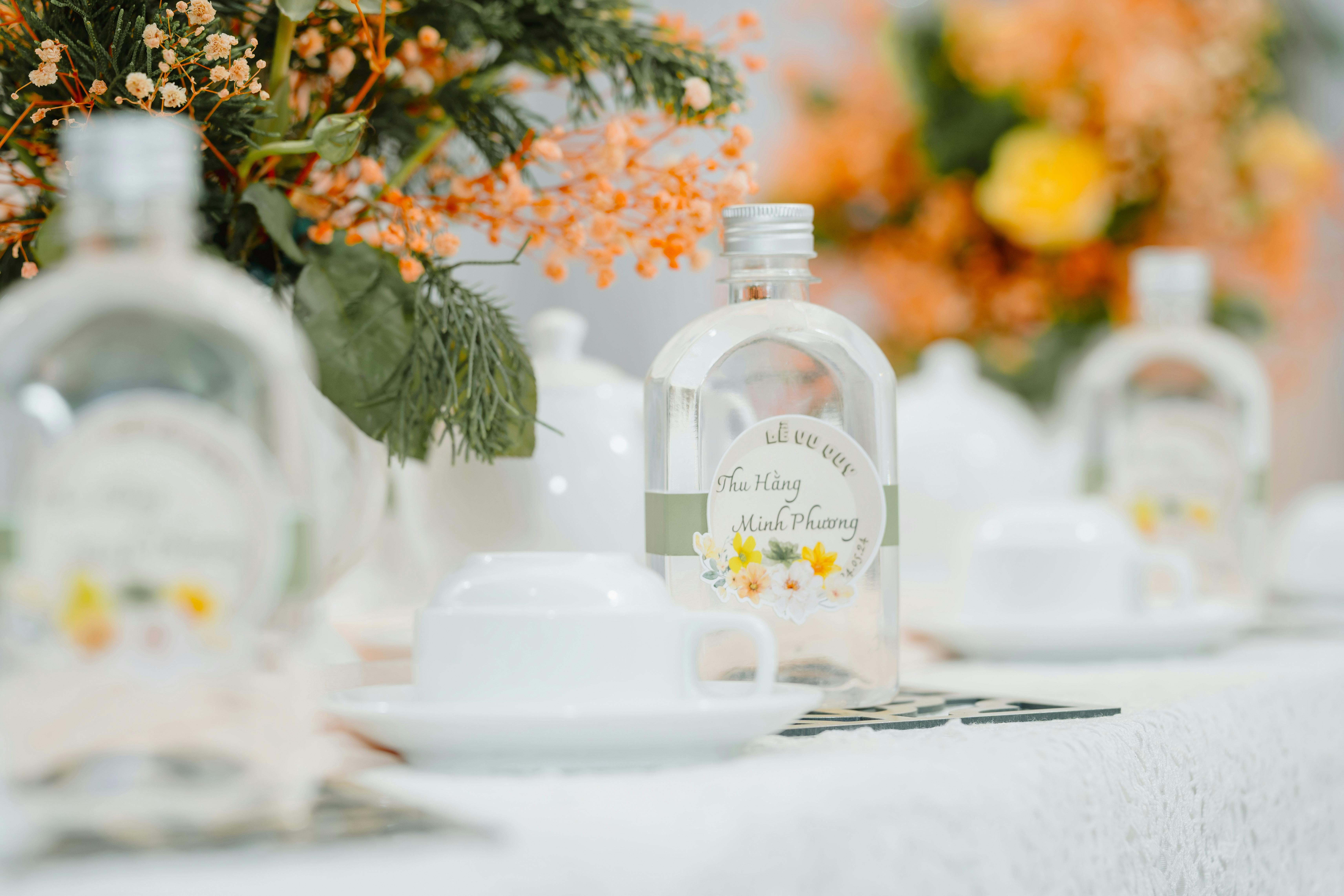 Close-up of a beautifully set table with floral decor and personalized bottles at an event.