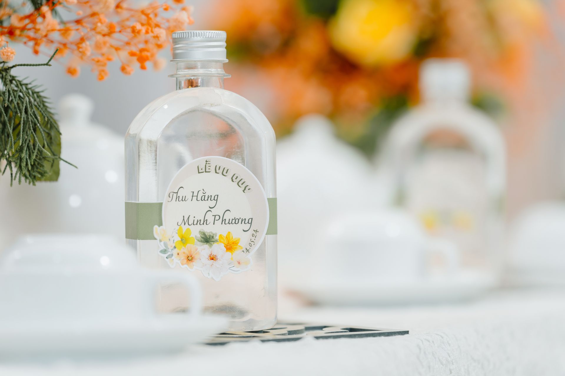 A beautifully designed wedding favor bottle featuring delicate floral details and elegant typography.