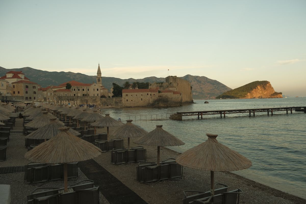 Beach umbrellas at sunset with the old town of Budva behind