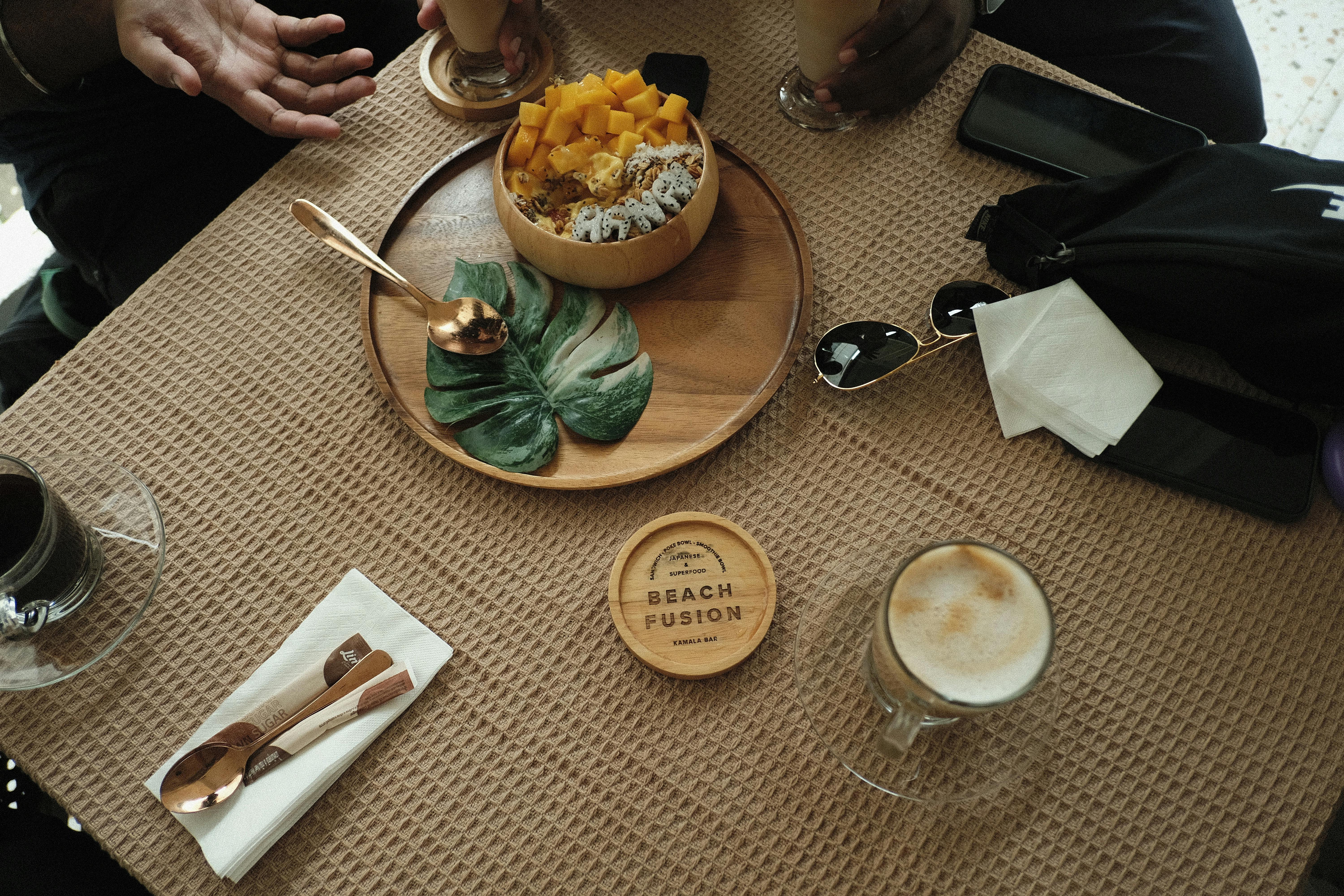 A tropical smoothie bowl with fresh mango and a cappuccino on a café table, Bangkok.
