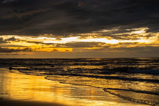 A mesmerizing sunset casting golden reflections over the ocean waves at the beach.