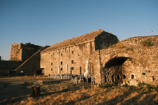 Historic Shkodër Castle in Albania at sunset with empty outdoor seating.