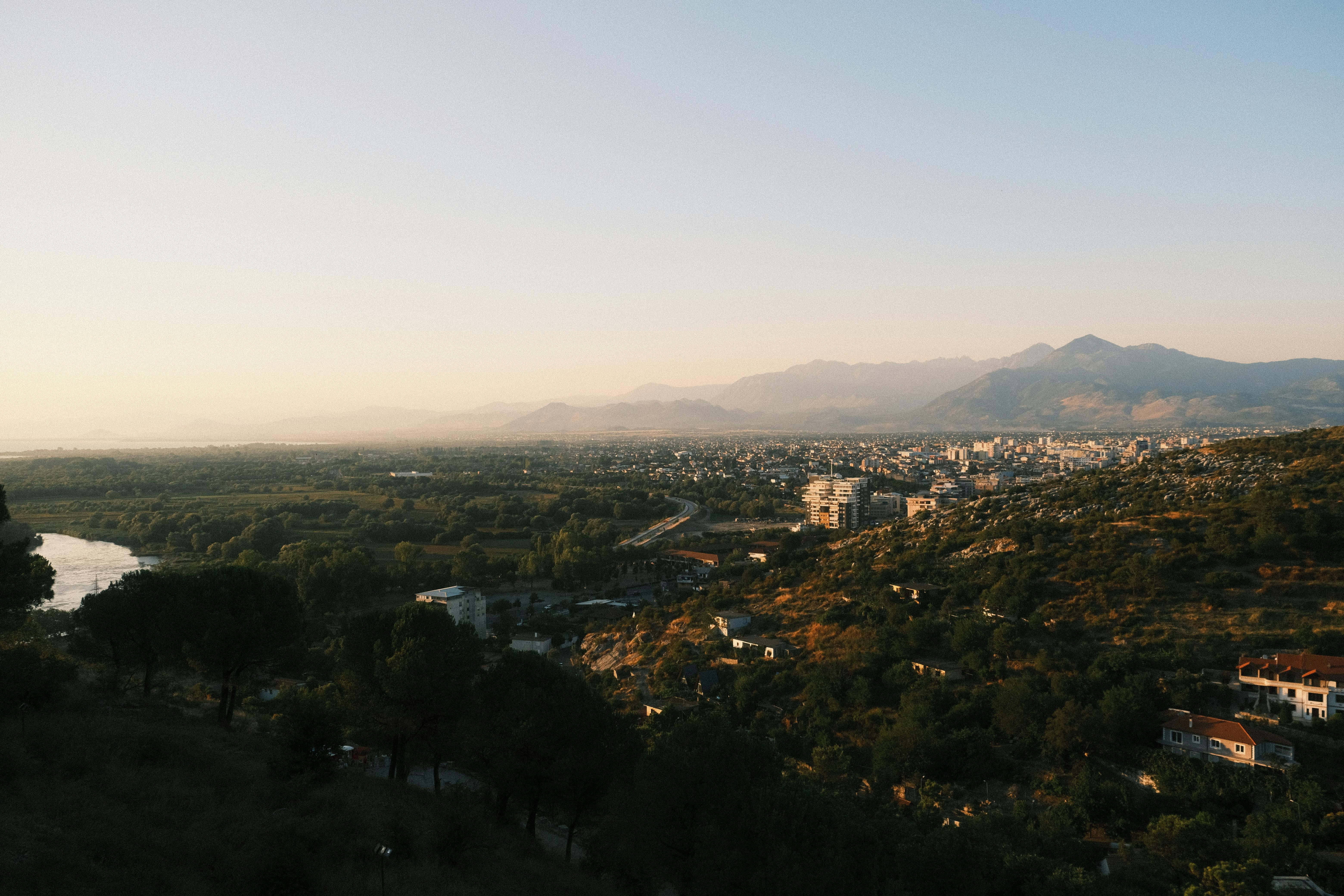Panoramic view of Shkodër, Albania at sunset with mountains and cityscape.