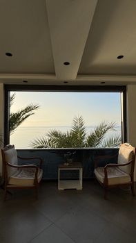 Elegant lounge with palm view over the ocean at sunset, serene and inviting.