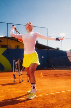 Dynamic shot of a young female tennis player serving on an outdoor clay court.