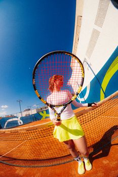 Bright and dynamic portrait of a female tennis player with a racket on an outdoor court under a vivid blue sky.