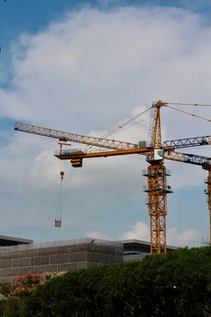 Tower crane operating at an urban construction site under a blue sky, symbolizing growth and development.