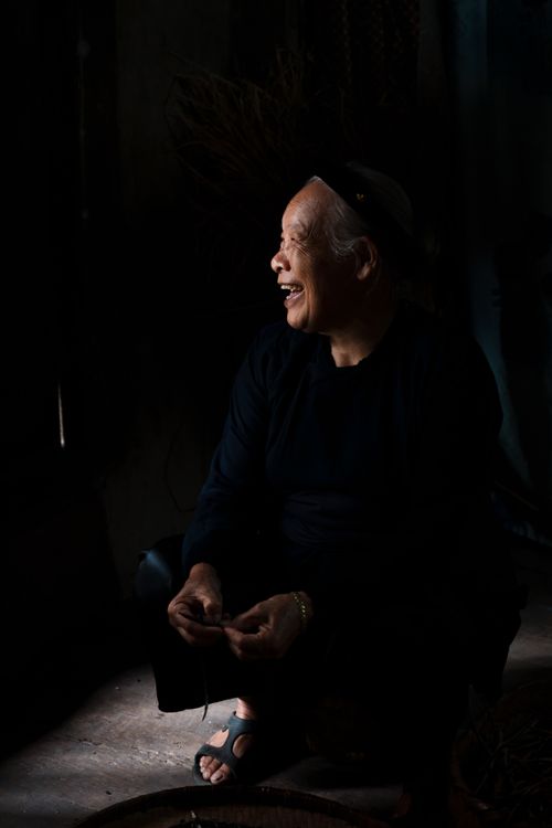 Free A senior woman smiles warmly, captured in a dimly lit room, creating a serene ambiance. Stock Photo