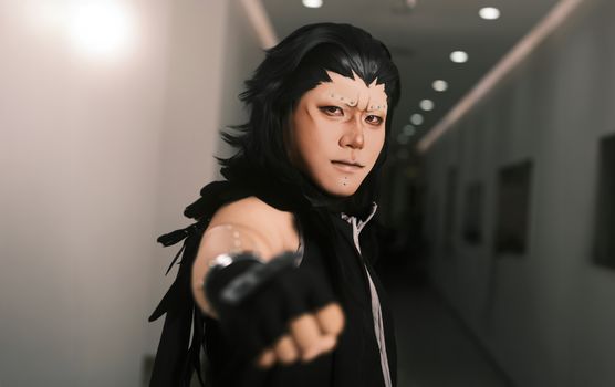 Captivating portrait of a cosplayer with intricate makeup in a dimly lit hallway.