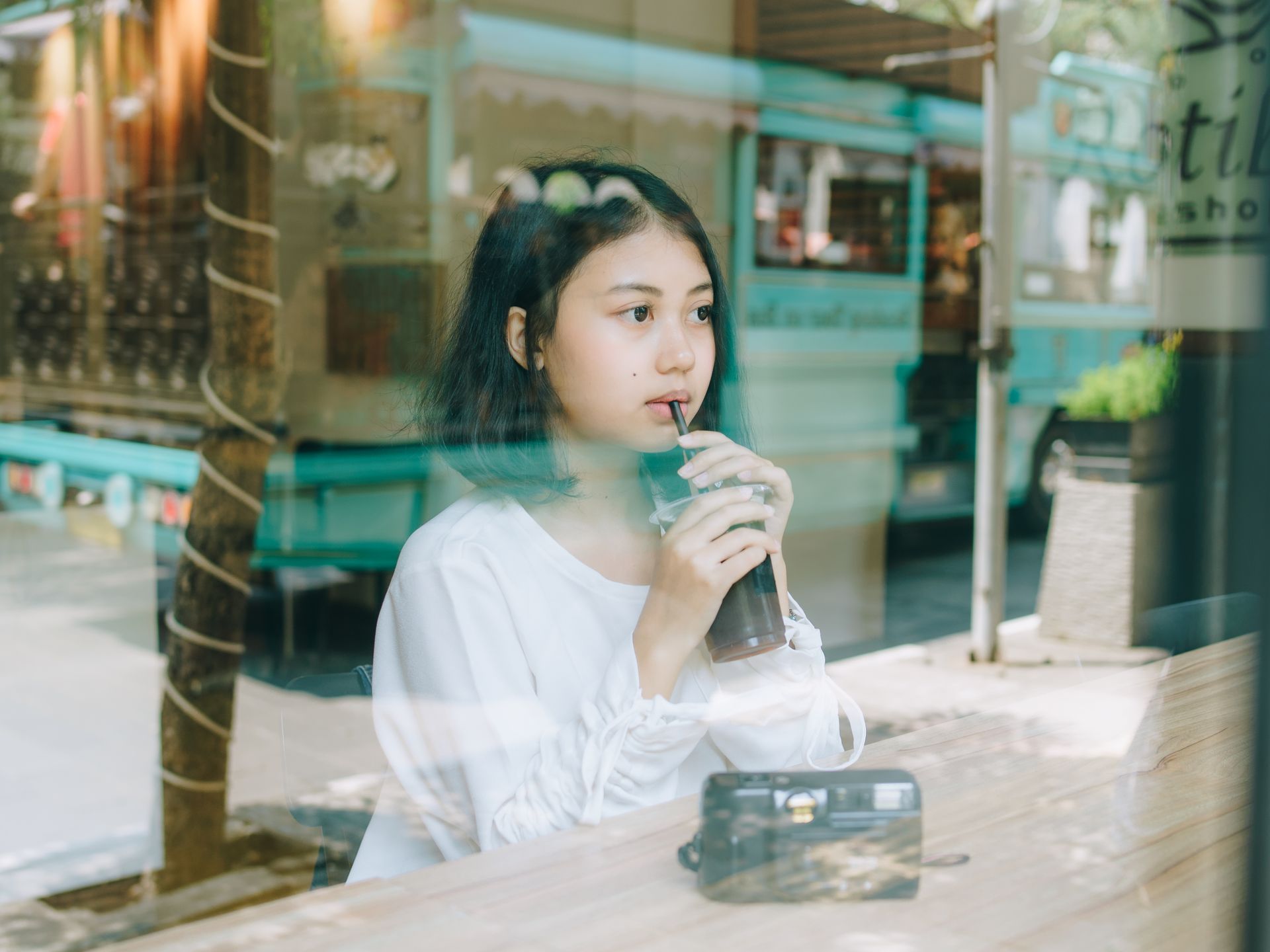 A young woman enjoys a drink at a cafe in Bandung, Indonesia, capturing a relaxed moment.