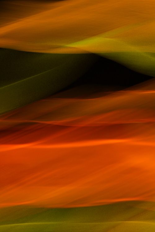 Free Dynamic abstract image showing colorful light streaks in orange and green hues, creating a fluid motion effect. Stock Photo