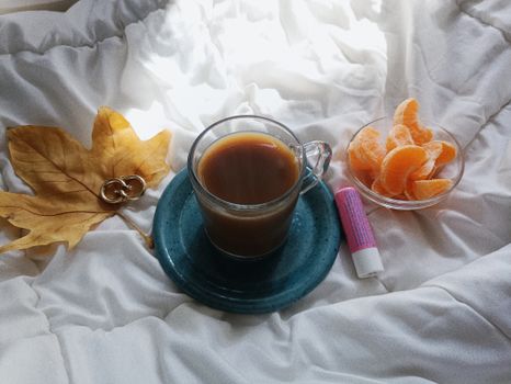 Inviting morning scene with coffee, citrus, and cozy bedding highlighting a relaxing autumn vibe.
