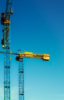 Bright construction cranes against a blue sky in Budapest, Hungary.