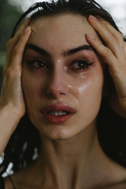 Free Close-up portrait of a woman with wet hair and tearful eyes, expressing intense emotion. Stock Photo