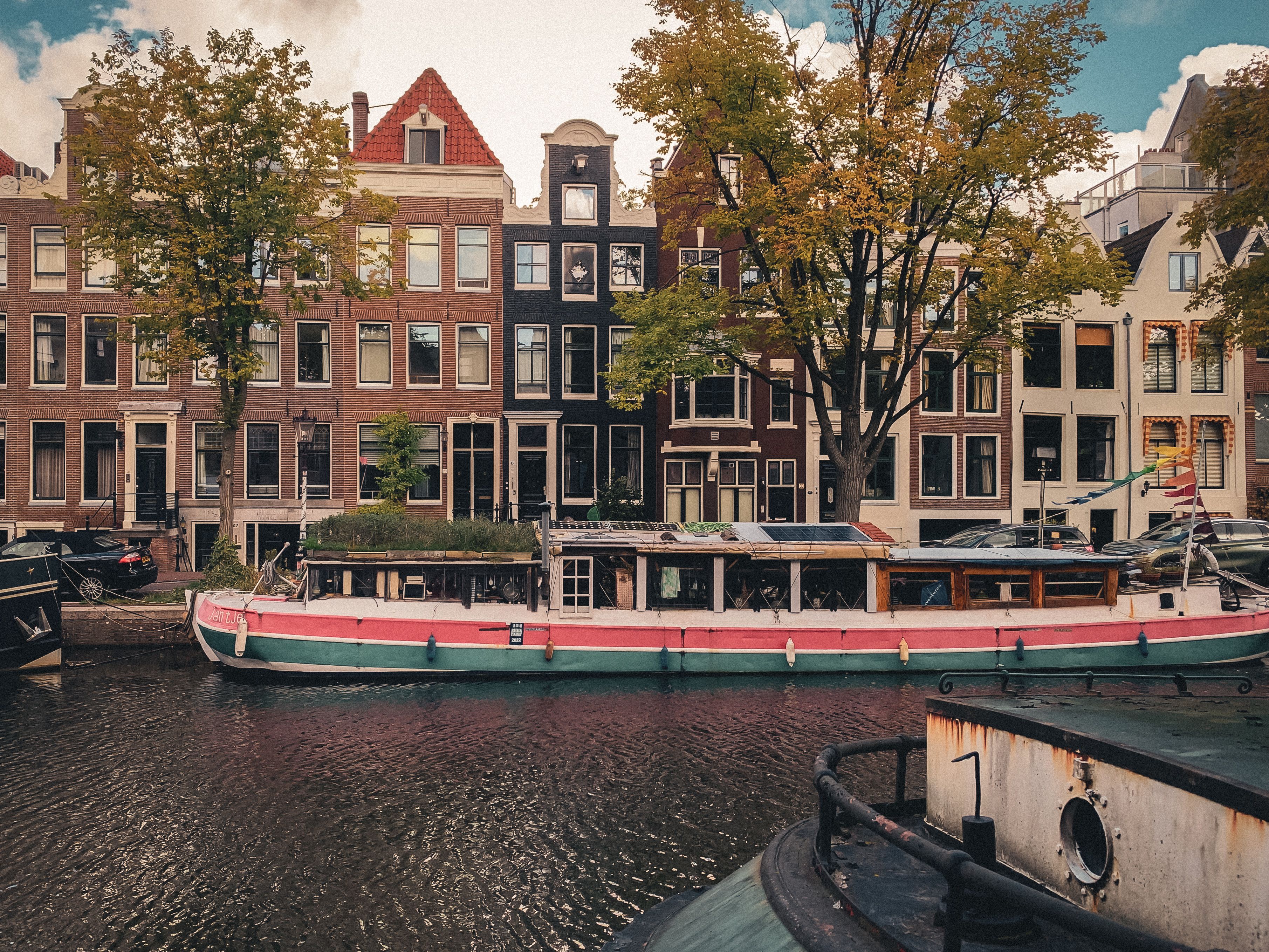 Tranquil scene of Amsterdam canal with iconic houseboats and Dutch architecture. - La Haya