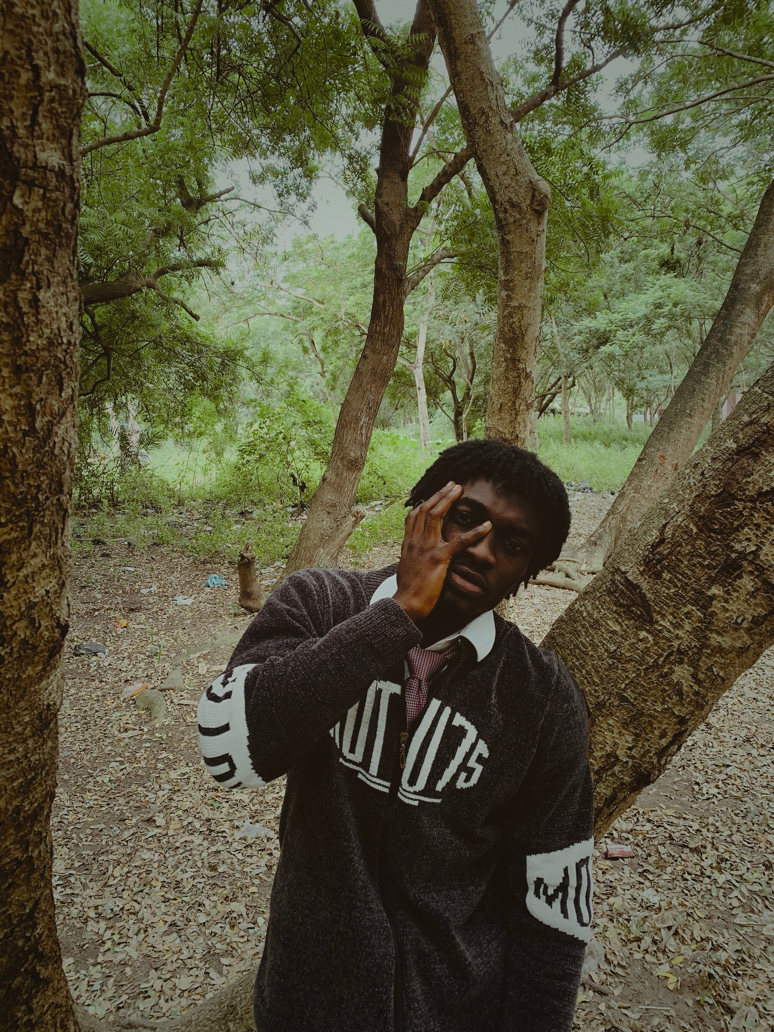 Man standing thoughtfully amidst trees in a serene forest setting.
