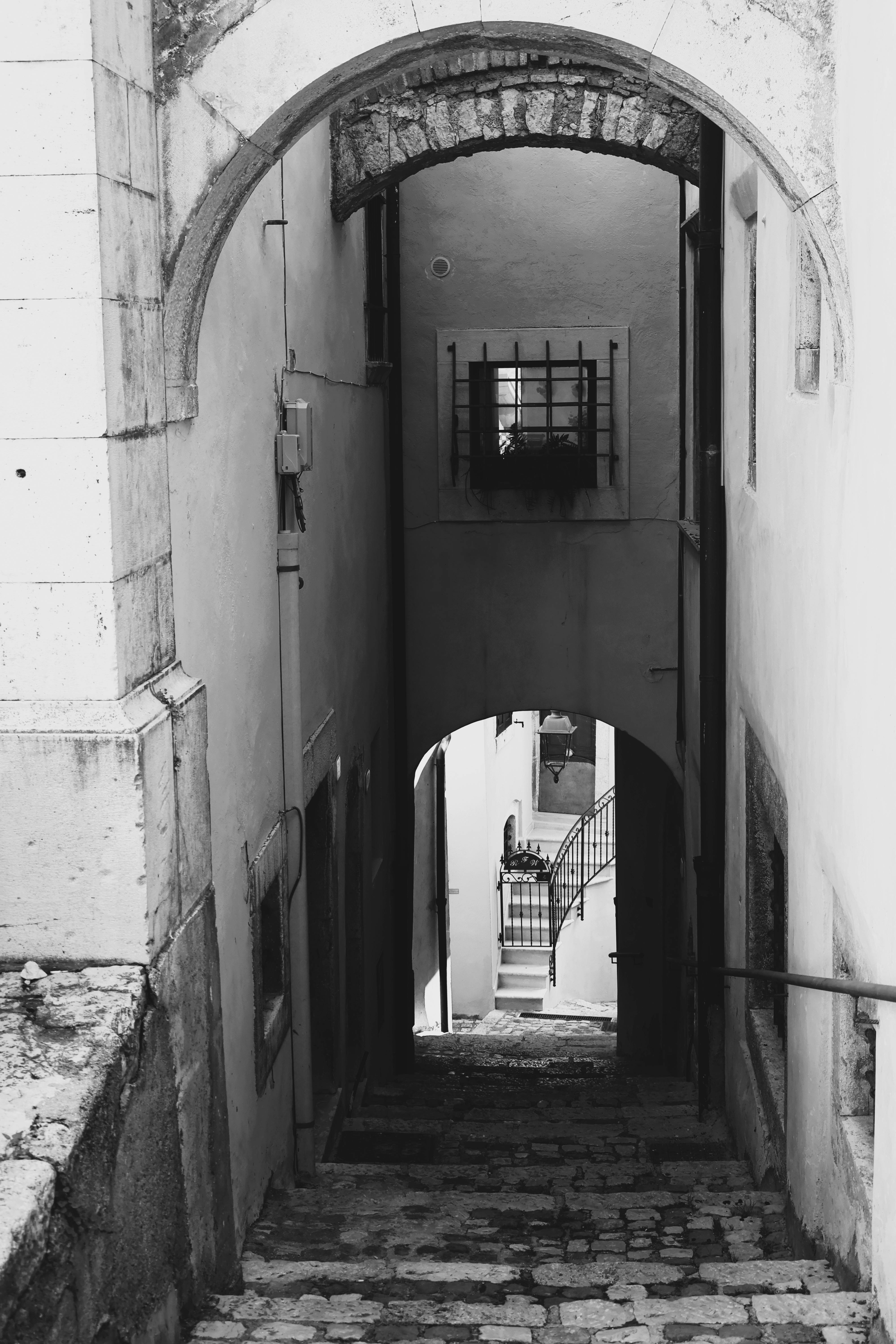 grátis Foto em preto e branco de um beco estreito com escadas de pedra em L'Aquila, Itália. Foto profissional