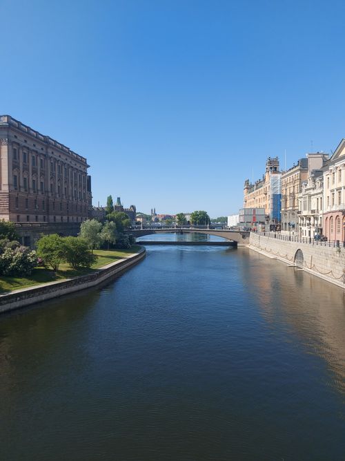 Free A picturesque river scene with historic buildings in a city center under clear blue sky. Stock Photo