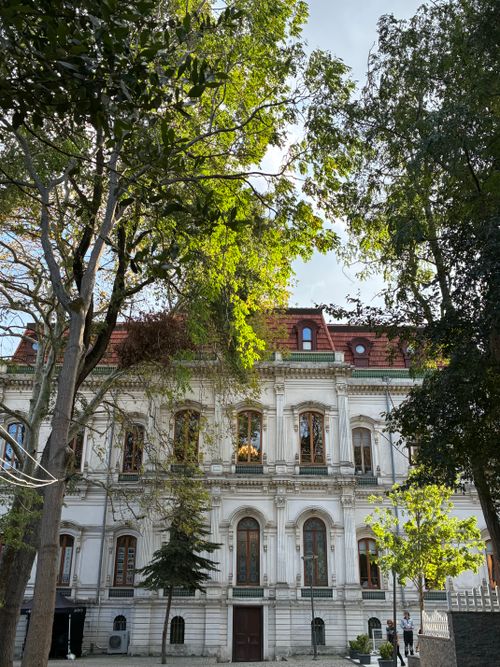 Free Elegant historic building surrounded by lush greenery under a bright blue sky. Stock Photo