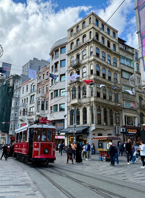 Free Capture of a historic red tram on Istanbul's lively Istiklal Avenue, surrounded by classic architecture and vibrant street life. Stock Photo
