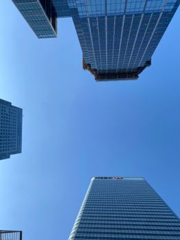 Looking up at skyscrapers in Canary Wharf, London on a clear day, showcasing modern architecture.
