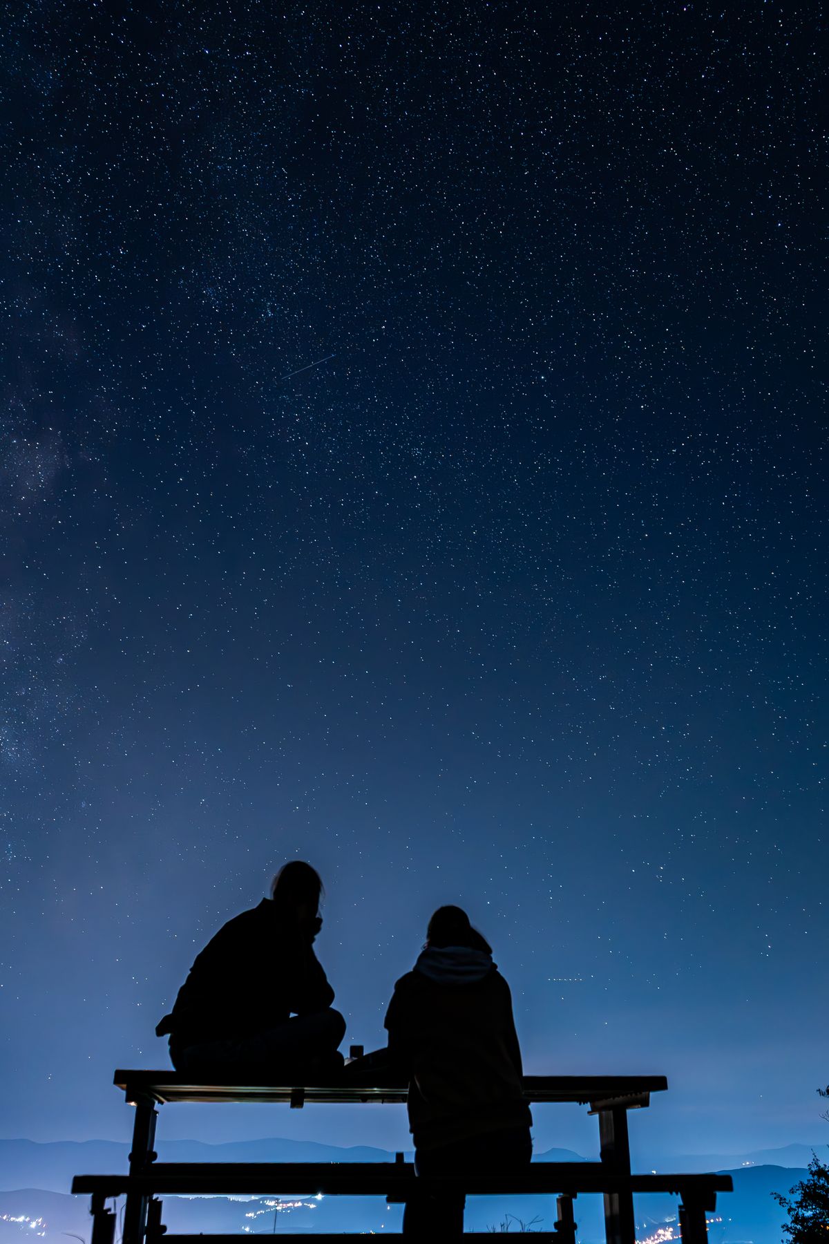 Two silhouetted stargazers under a clear night sky full of stars on a winter date