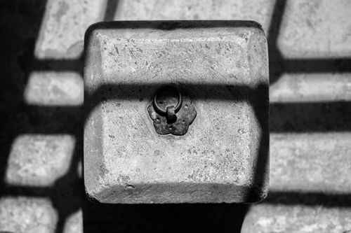 Free Black and white photo of a vintage lock set in a stone block with dramatic shadows cast over it. Stock Photo