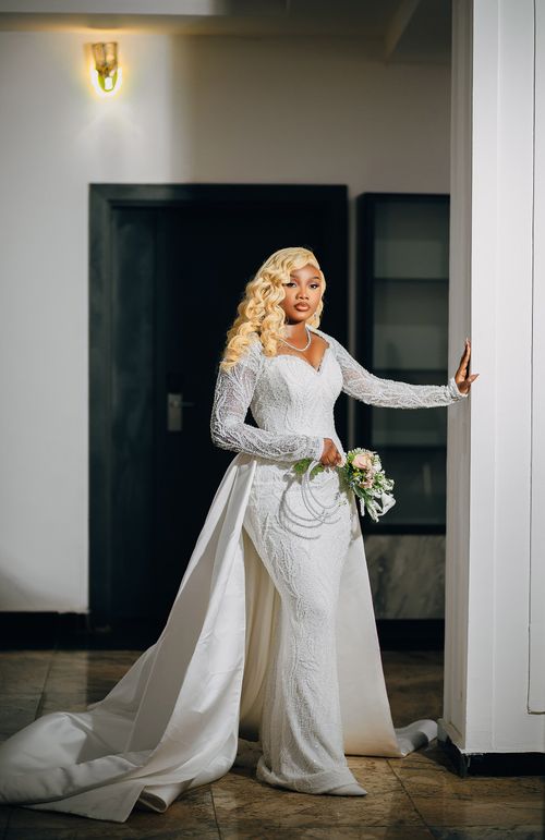 Free Beautiful bride in white gown holding bouquet indoors, exuding elegance. Stock Photo