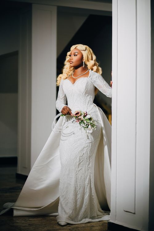 Free A beautiful bride posing in an exquisite white lace wedding dress indoors. Stock Photo