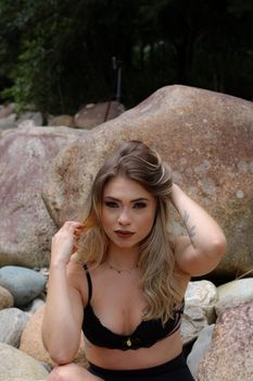 Stylish woman posing outdoors by rock formation in nature setting.