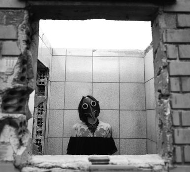 Black and white photo of a masked figure standing inside a dilapidated tiled room.